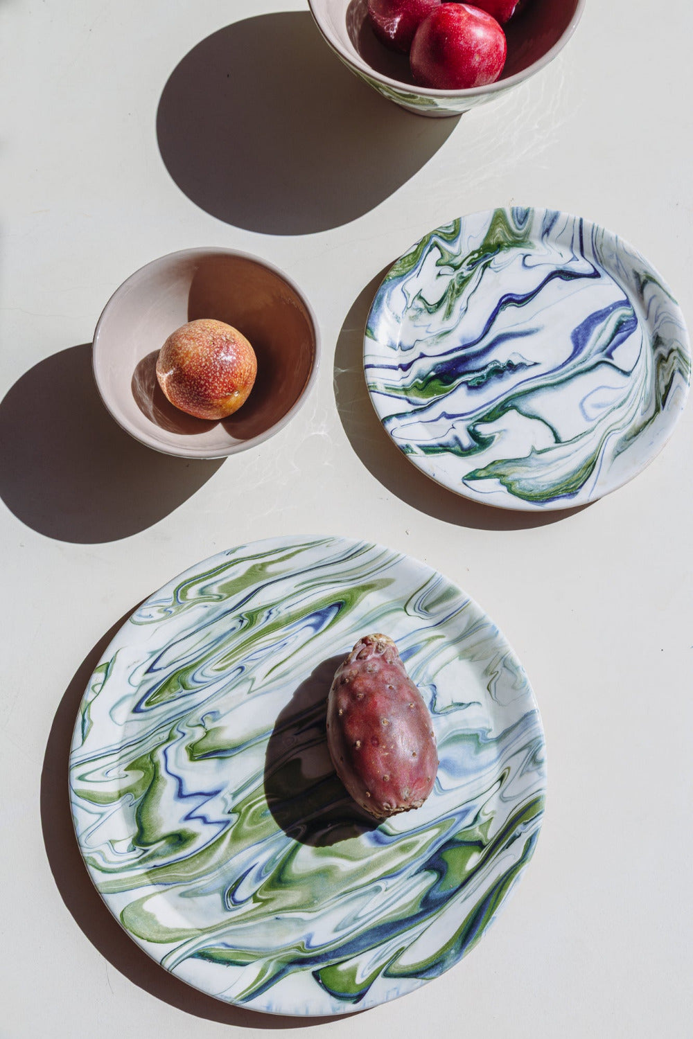 Two ceramic plates with marbled green and blue design on a white surface.