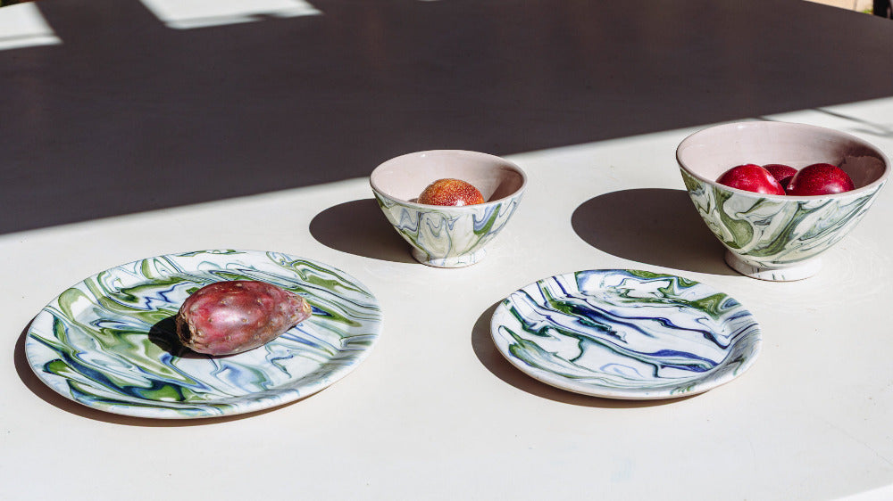 Set of ceramic plates and bowls with decorative patterns on a white surface.