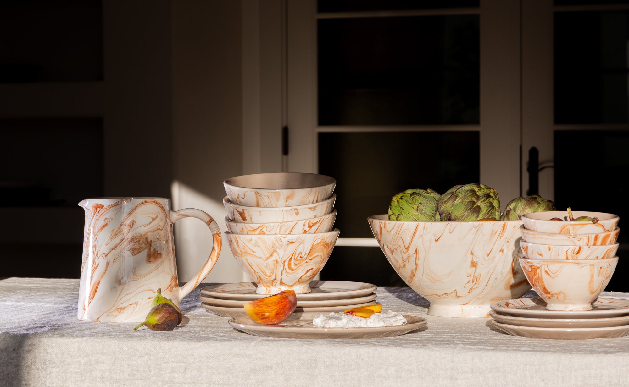 Dishware set with bowls, plates, and a pitcher on a table.