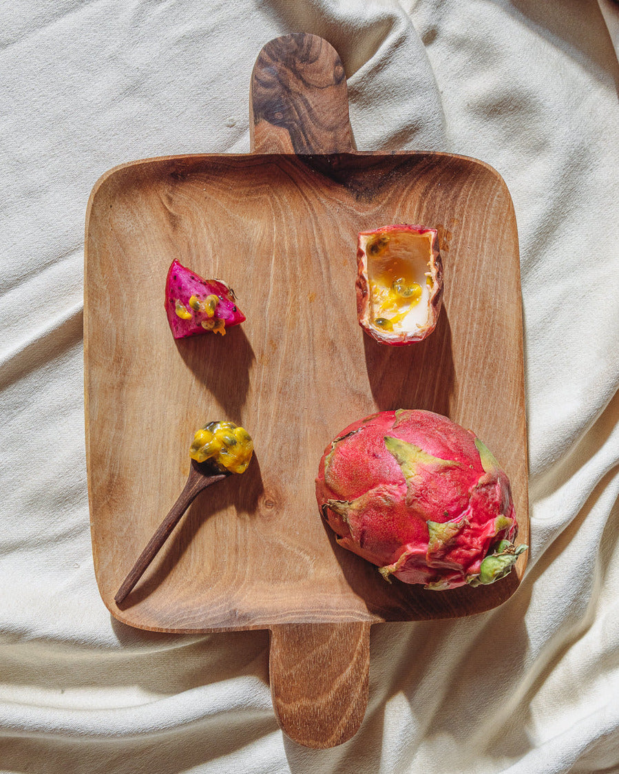 Wooden cutting board with dragon fruit on a light fabric background