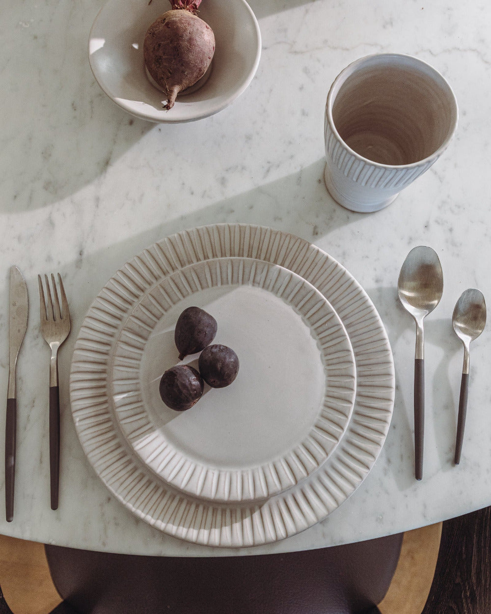 Dinner setting with a plate, cup, and cutlery on a marble surface