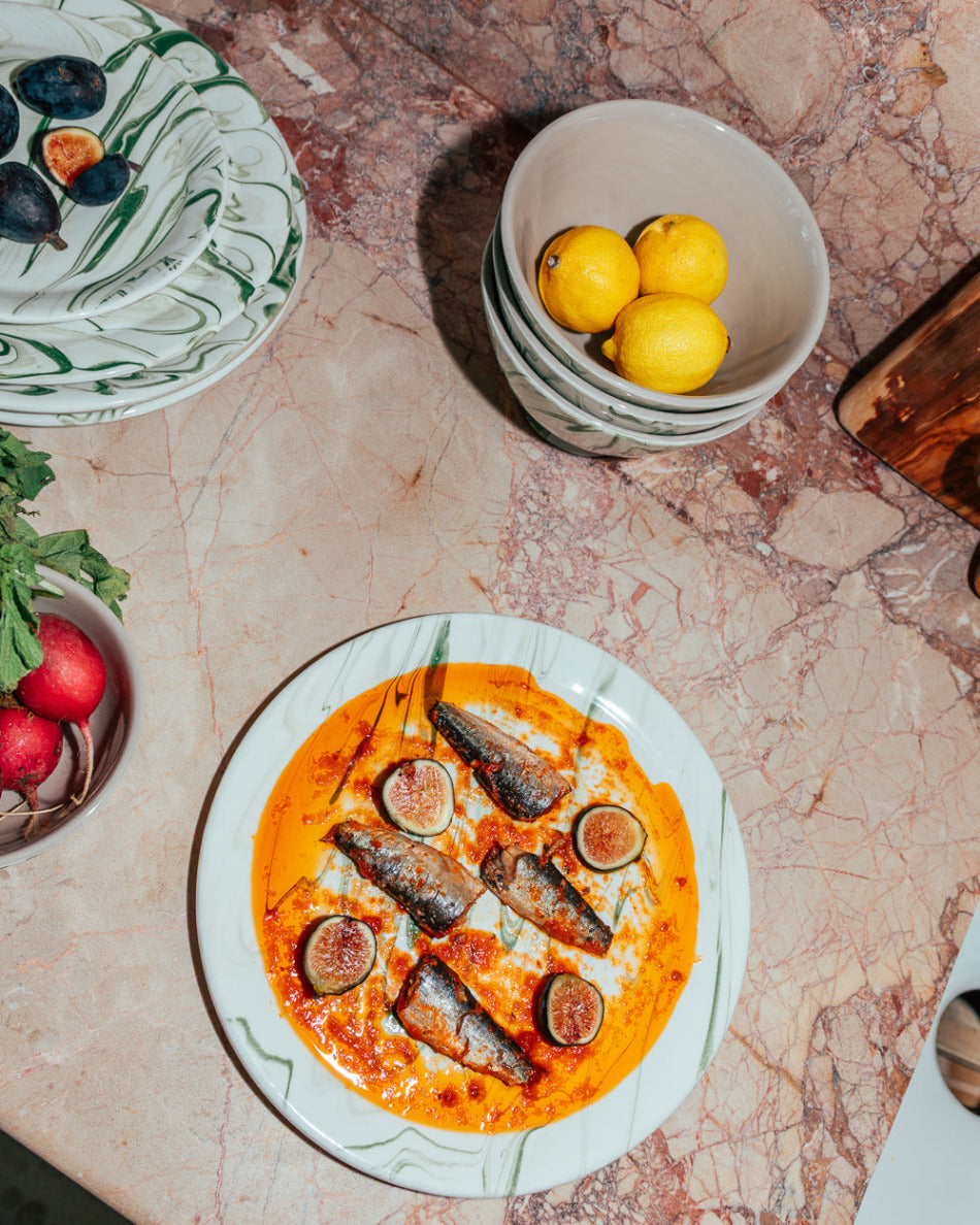 Pizza with figs and olives on a marble table with lemons and radishes.