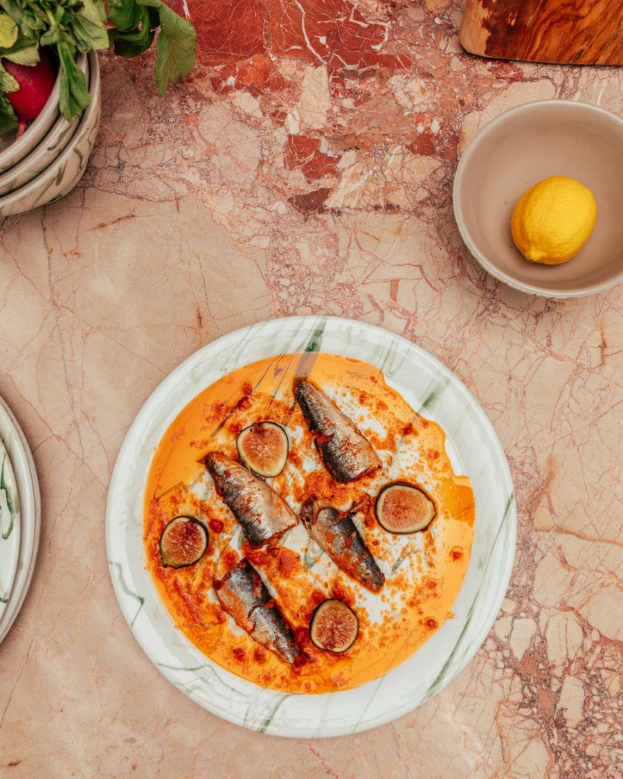 Plated dish with fish and figs on a marble surface