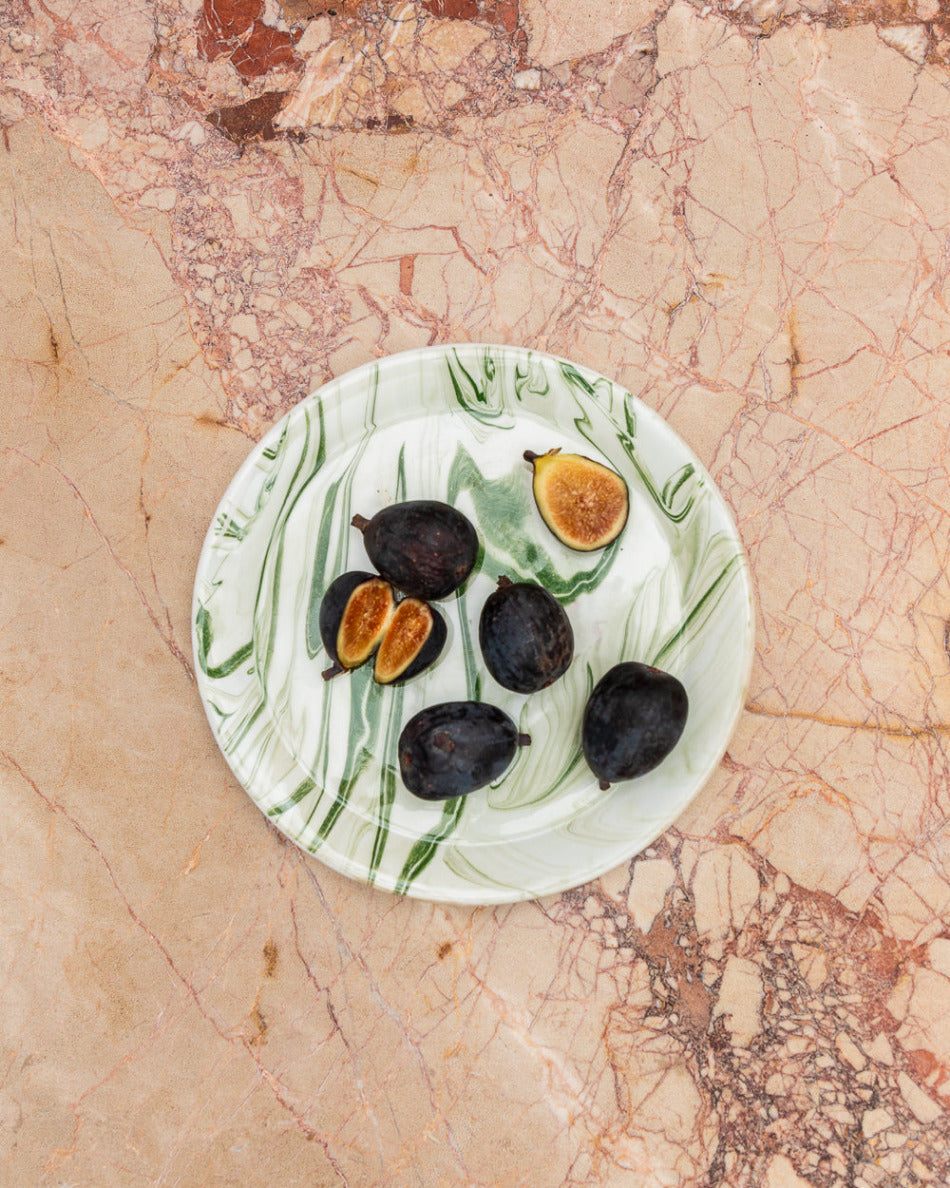 Figs on a decorative plate with leaf patterns on a marble surface