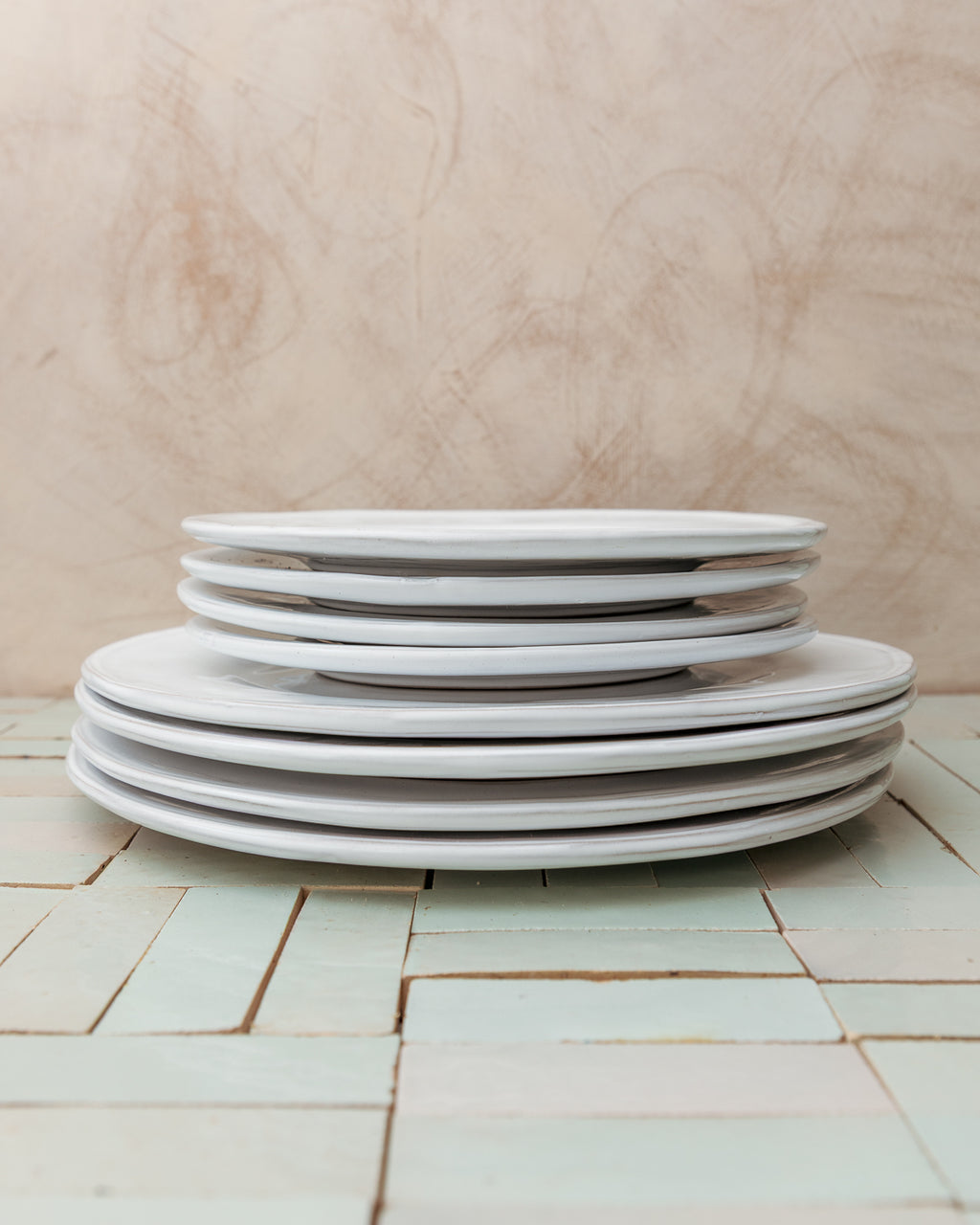 Stack of white ceramic plates on a tiled table with a wooden wall background