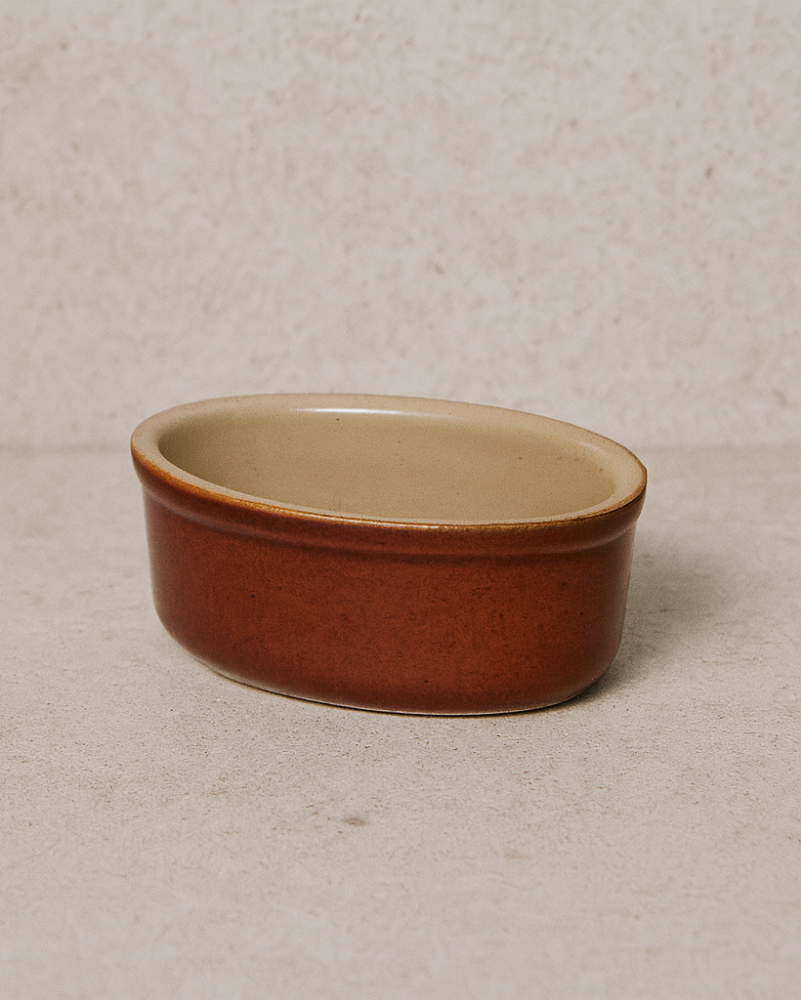 Small ceramic bowl with brown exterior and beige interior on a beige background