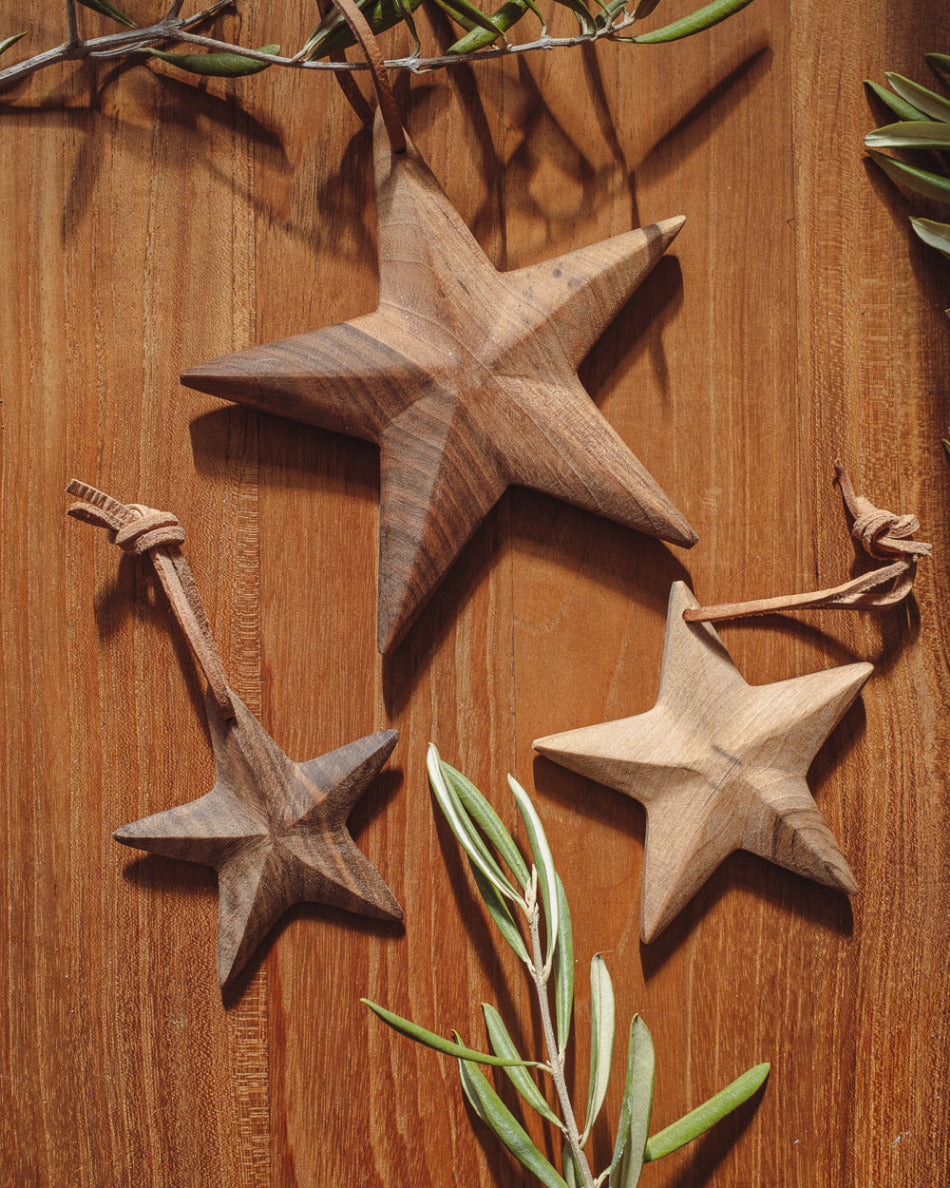 Wooden star decorations on a wooden surface with green leaves.
