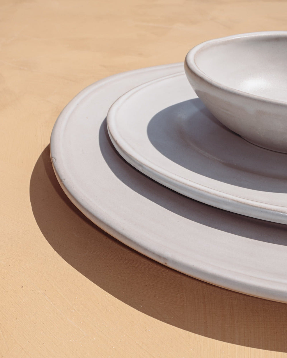 Stack of white ceramic plates and bowls on a beige background