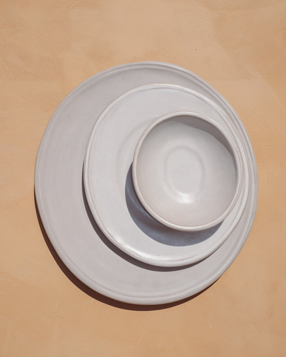 table setting of white ceramic oval bowls  and plates on a beige backgroundbackground