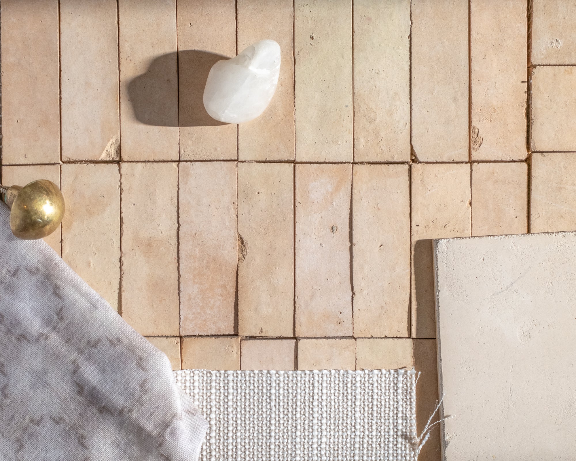 Close-up of a unglazed zelliege tiled counter with fabric, stone and metal samples.