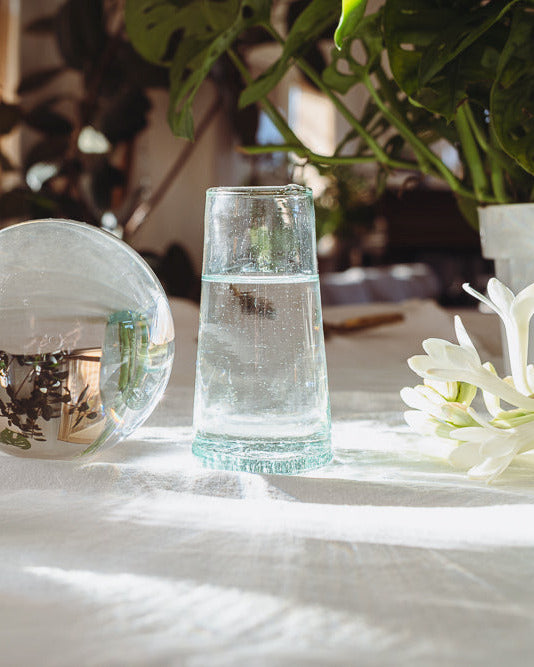 Clear recycled glassware on a table with natural light and blurred background