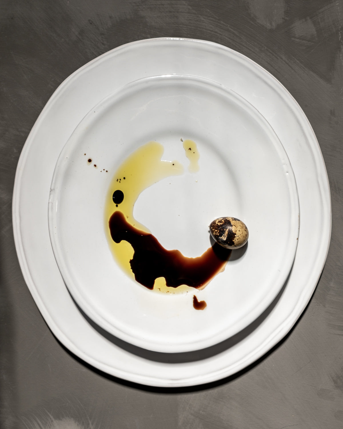 White plate with a small dessert and sauce on a dark surface