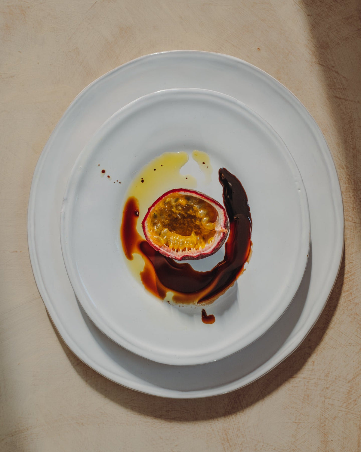 Half-eaten passion fruit with chocolate sauce on a white plate