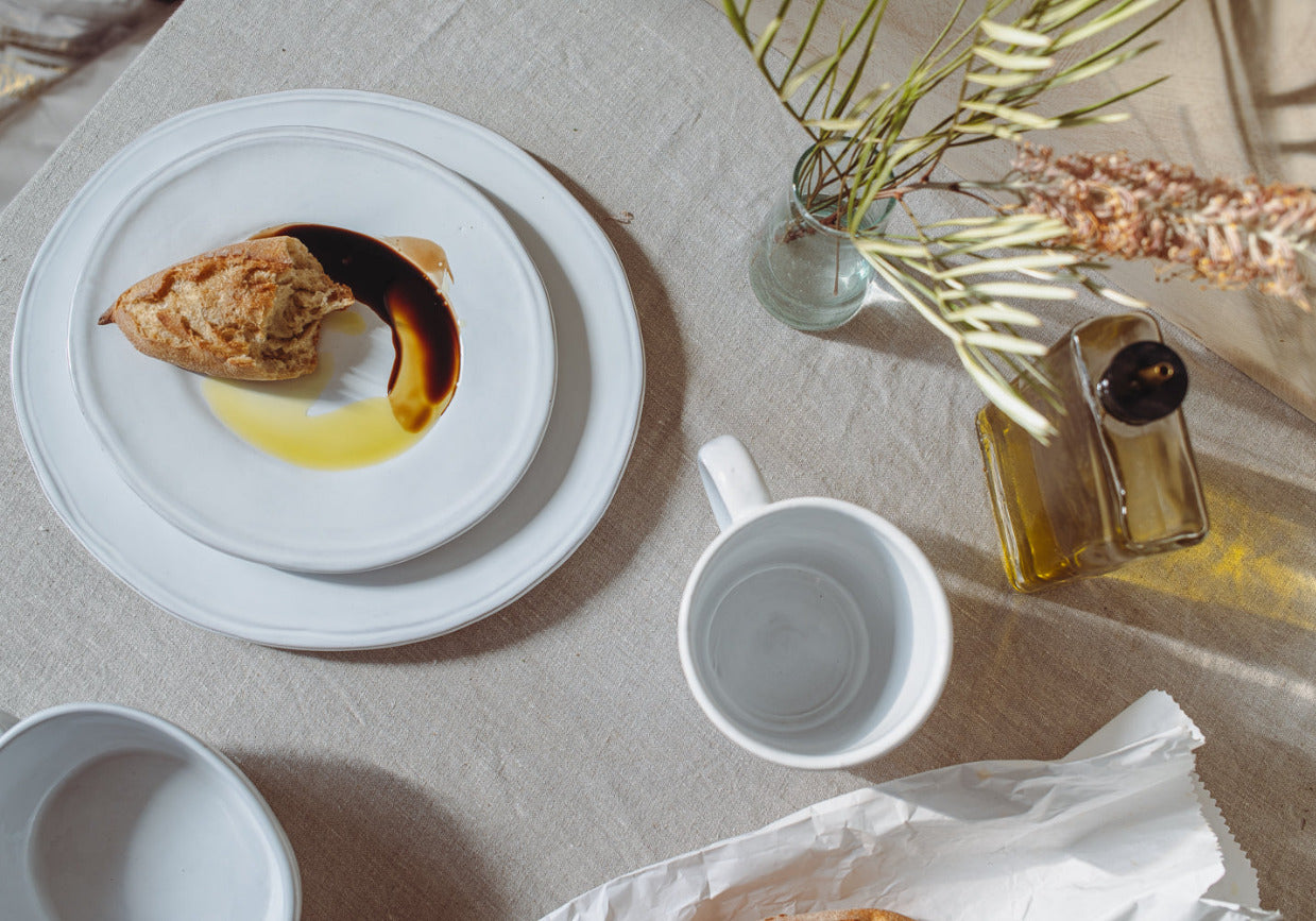Table setting with a plate of food, mug, and decorative elements on a light surface.