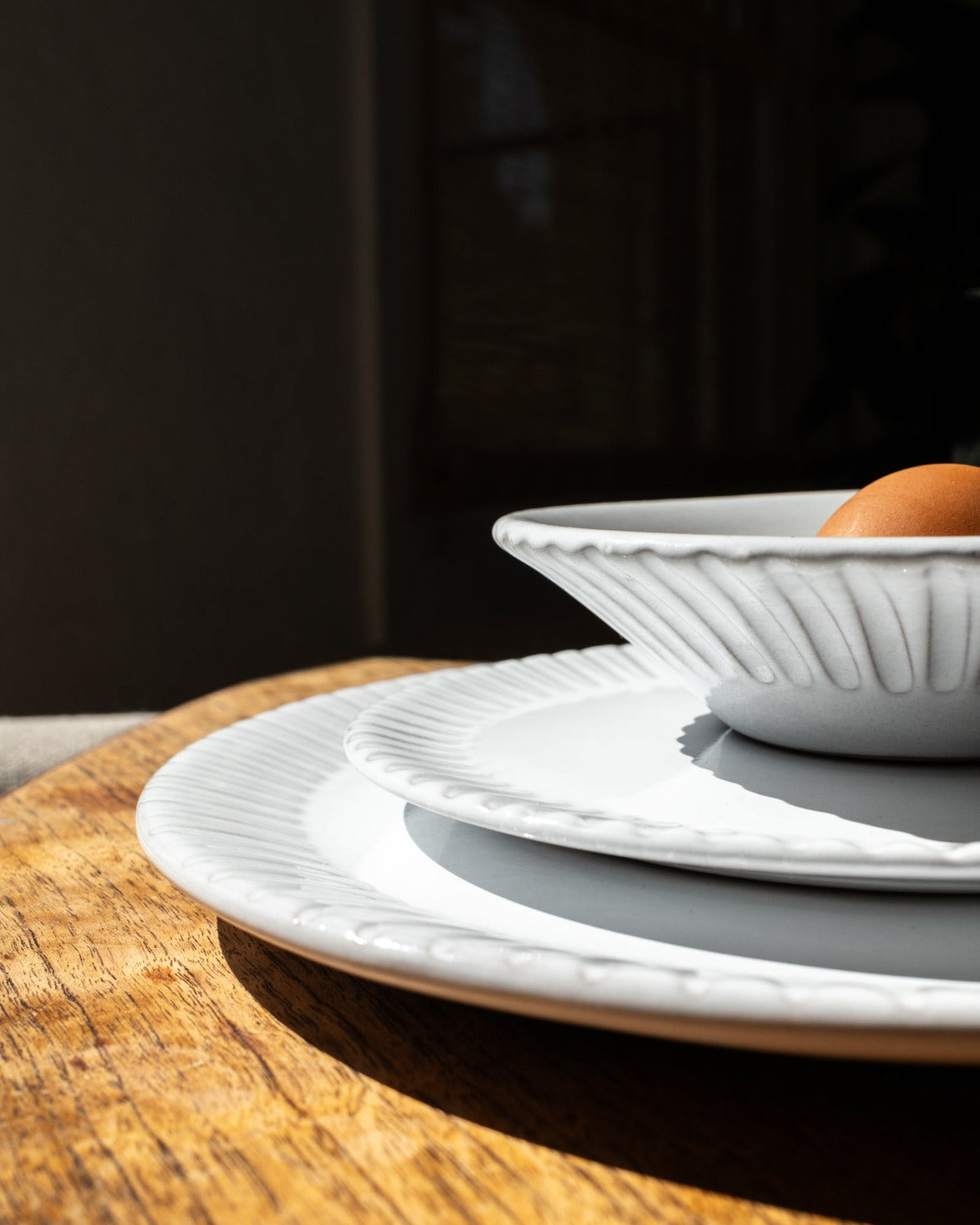 White ceramic plates and bowl on a wooden surface with a dark background