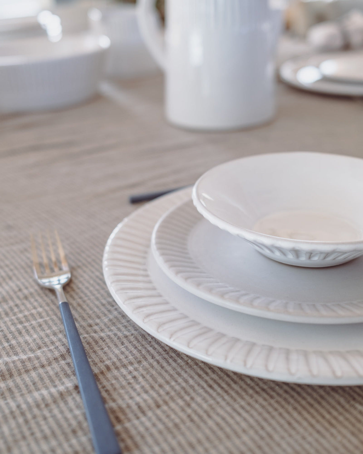 White ceramic plates stacked on a textured beige placemat with a fork.
