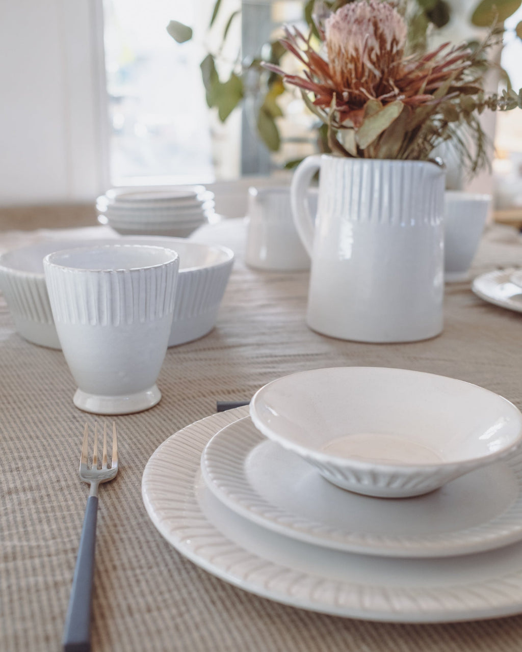 White ceramic tableware set on a dining table with a neutral background
