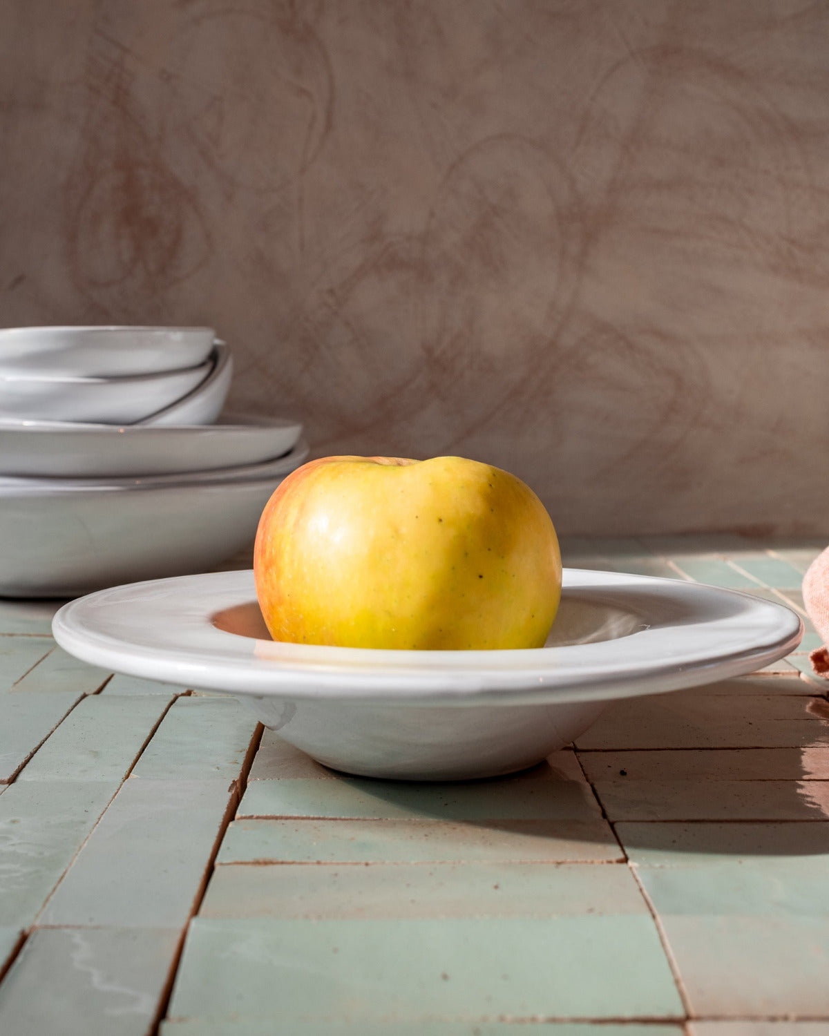 Yellow apple on a white ceramic plate with a rustic background