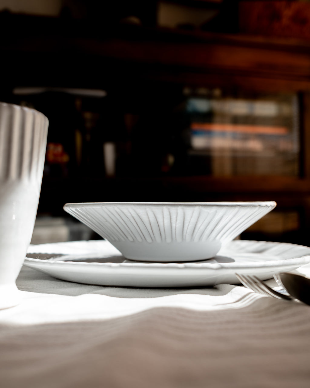 White ceramic plates and a cup on a table with a blurred background