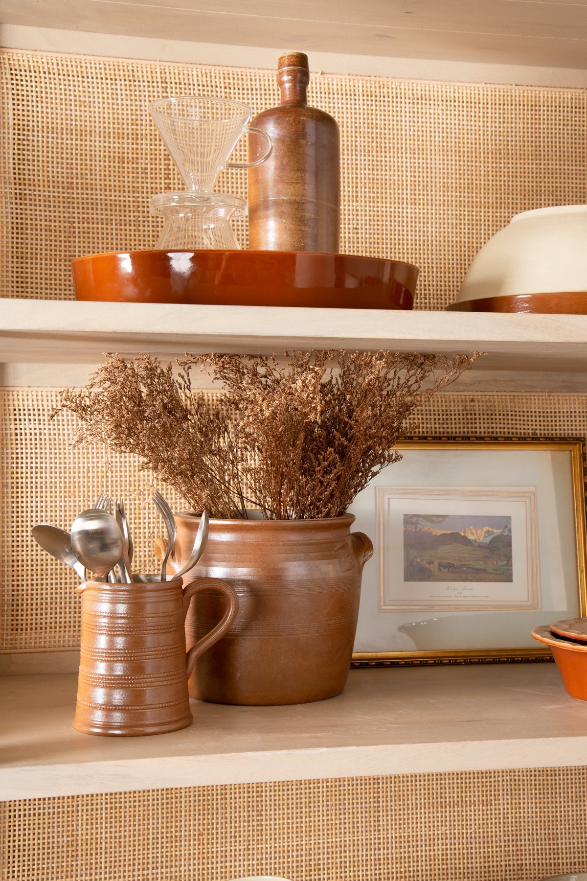 Decorative shelf with ceramic items, a framed picture, and a woven background