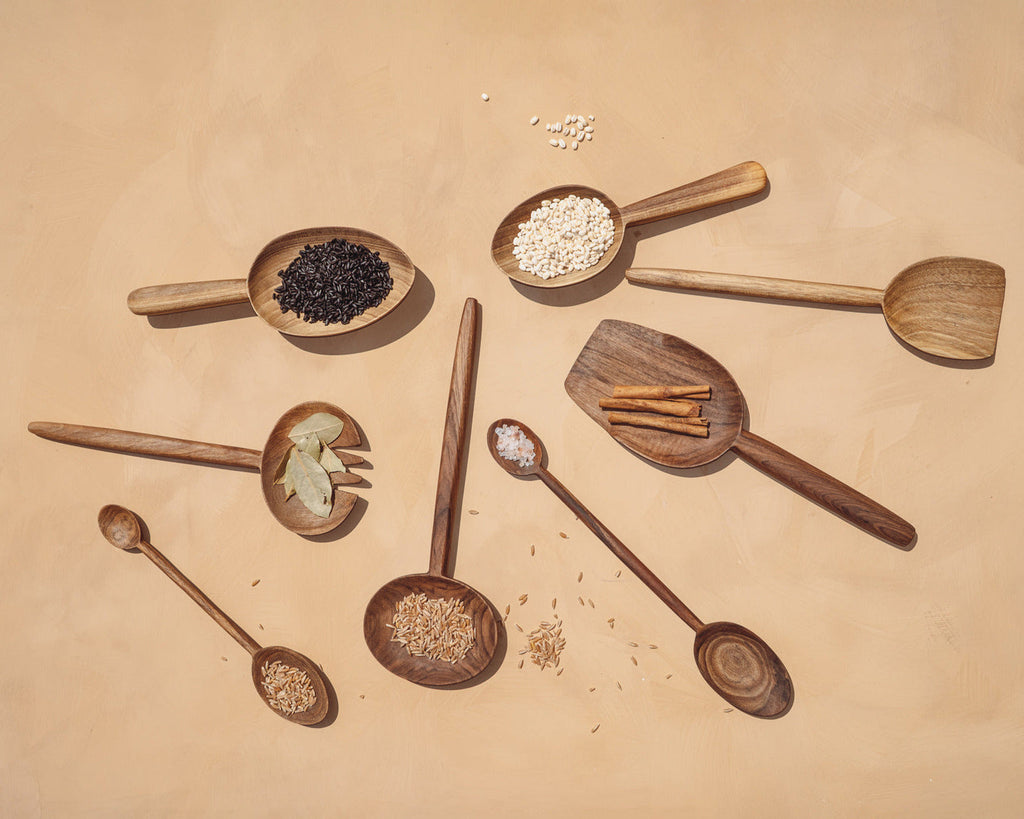 Wooden spoons with various spices and ingredients on a beige background